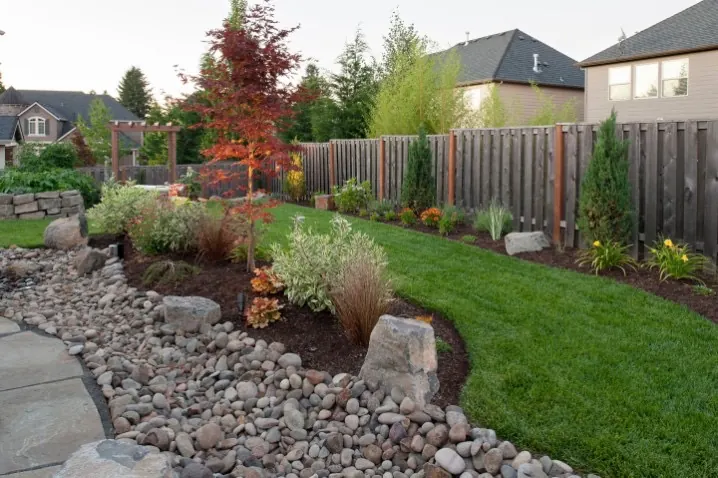 Backyard landscape design with Japanese maple, ornamental grasses, and dry creek bed - Landscaping Freeport FL