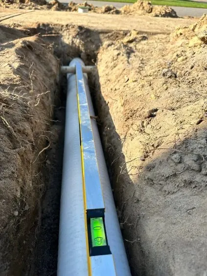 Large drainage pipe in trench with level for proper grading - HT Outdoor Living