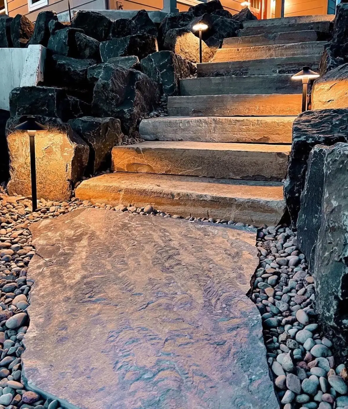 Natural stone steps with pathway lighting and boulders at night - Landscape Lighting Freeport FL